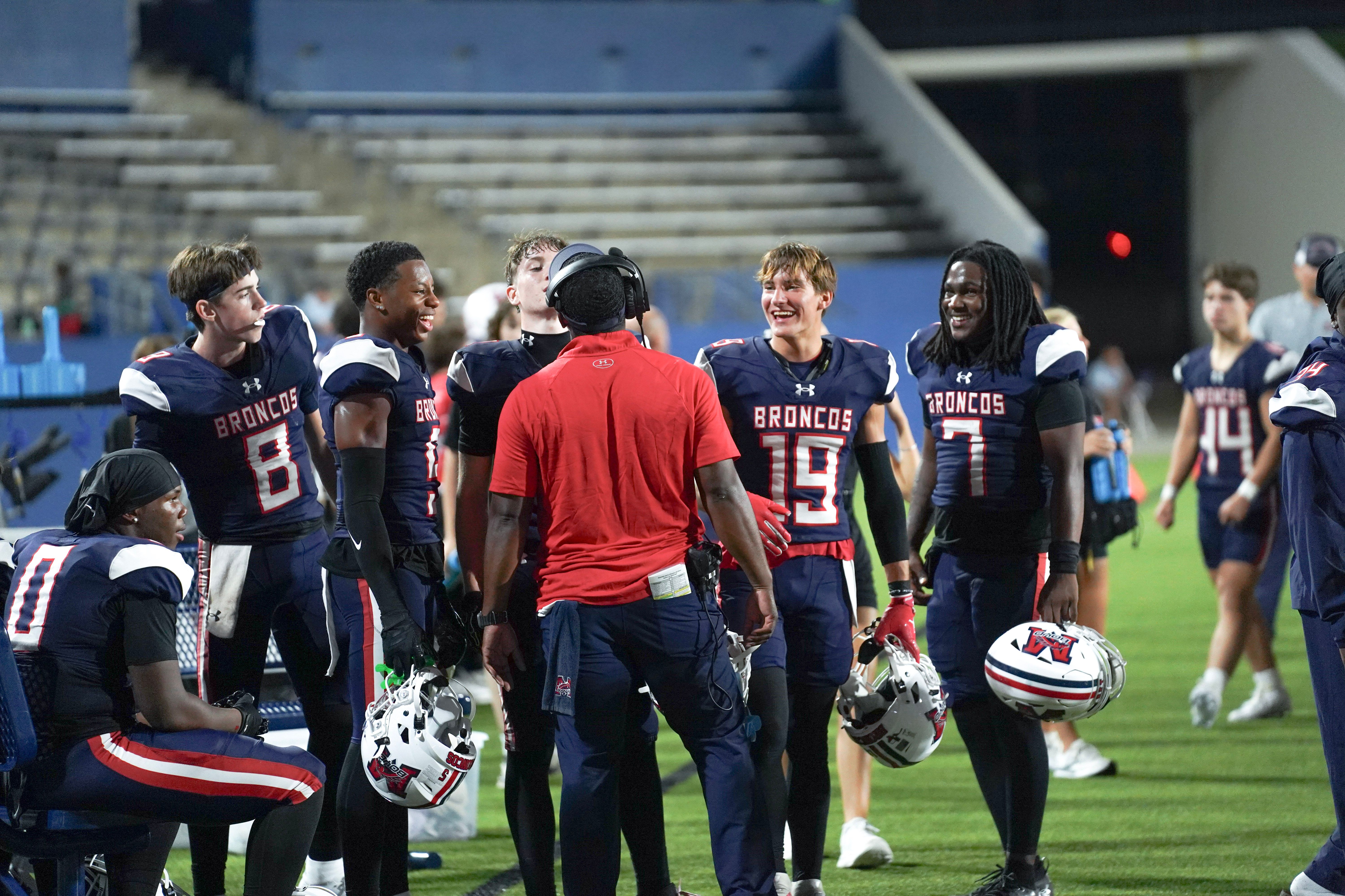 McKinney Boyd Broncos players and coaching staff sharing a laugh on the sideline